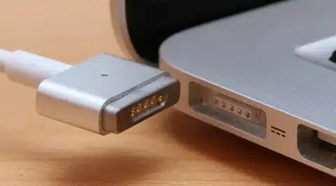 “MagSafe 2 adapter being plugged into MacBook charging port closeup”