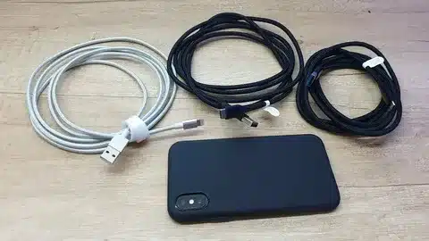 Multiple iPhone charging cables with Lightning connector and phone.
