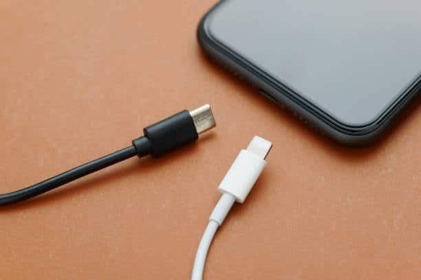 Black usb c cable and white lightning cable with smartphone
