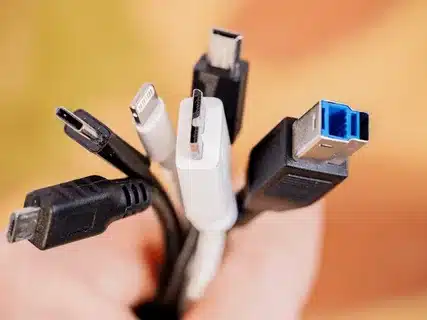 “Hand holding various USB cables including Type-C, Lightning, Micro-USB, Mini-USB, and USB 3.0.”