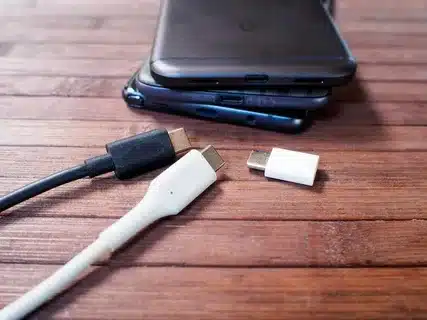 multiple Android phones with USB-C charging cables placed on wooden table