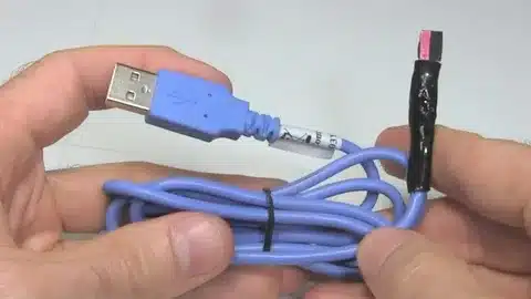 USB cable held in hand showing repair on exposed wire section