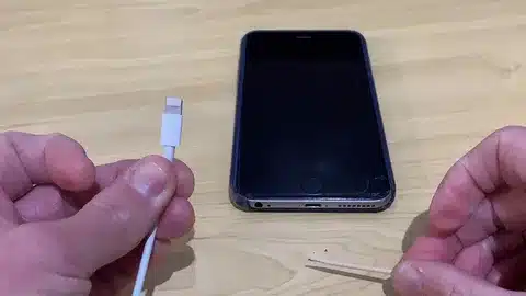person using toothpick to clean iPhone charging port before plugging charger wire