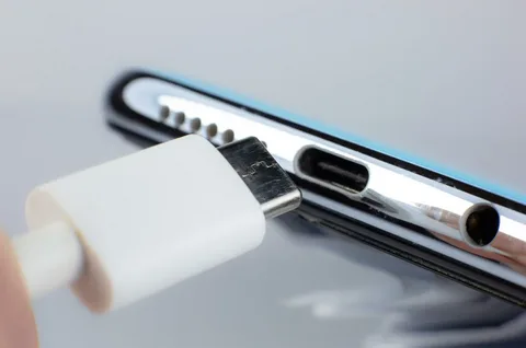close-up of silver smartphone with USB-C charging cable near port