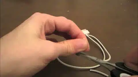 hand cutting a broken iPhone charger cable with scissors