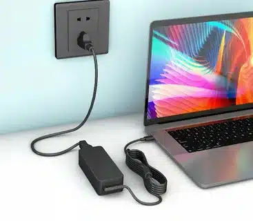 laptop charging with power adapter plugged into wall outlet