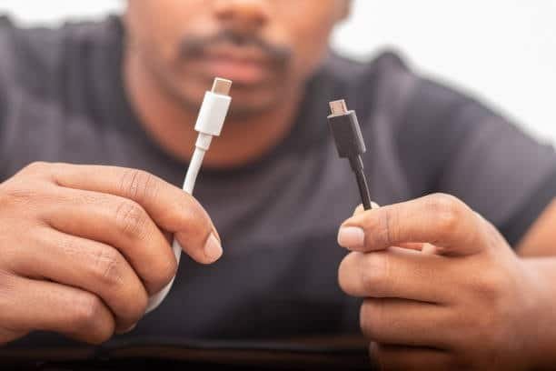 Person holding USB-C and micro USB cables for testing performance differences