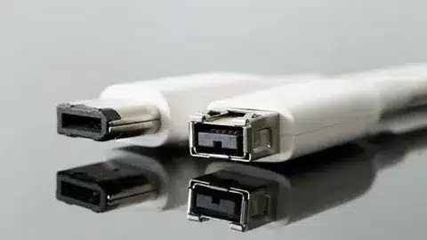 White FireWire cable connectors showing IEEE 1394 plug design on a reflective table